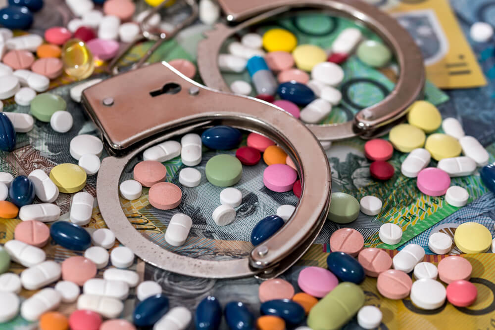 handcuffs and medications, showing disease as an expensive sentence