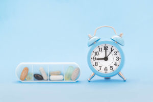 alarm clock and pills showing how an automatic pill dispenser would be easier